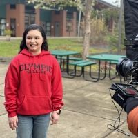Student on Shelton campus in red sweatshirt and smiling for the camera.