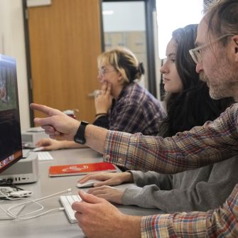 Filmmaking faculty and students editing a film on computer