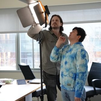 Film instructor and student setting up a panel light