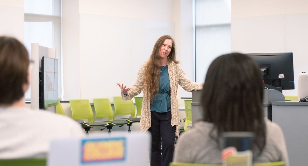 A female instructor teaching to a classroom filled with students